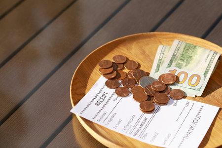 Wooden plate with payment for order and receipt on table, closeup. Leave tipの写真素材