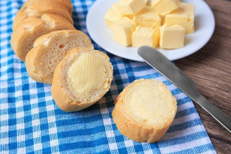 Tasty cut baguette with fresh butter on wooden table, closeupの写真素材