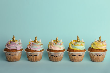 Many cute sweet unicorn cupcakes on light turquoise background, space for textの写真素材