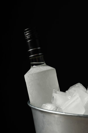 Bottle of vodka in metal bucket with ice on black backgroundの写真素材
