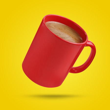 Red cup of coffee drink levitating on yellow backgroundの写真素材