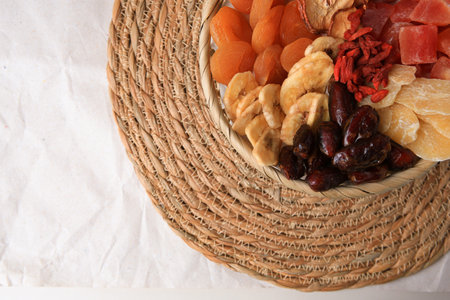 Wicker basket with different dried fruits on paper, top view. Space for textの写真素材