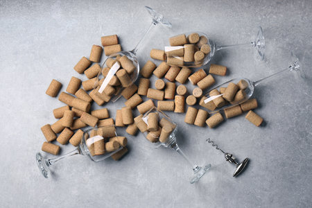 Glasses with many wine corks and corkscrew on light gray table, flat layの写真素材
