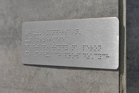 Silver plate with Braille text on gray wall, closeupの写真素材