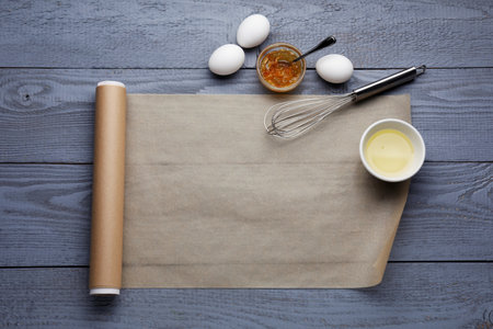 Baking parchment paper and ingredients on gray wooden table, flat lay. Space for textの写真素材