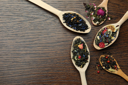 Flat composition with spoons of dried herbal tea leaves on wooden table. Space for textの写真素材