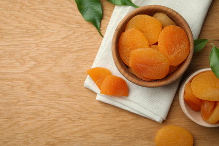 Tasty apricots with bowl on wooden table, flat lay and space for text. dried fruitsの写真素材