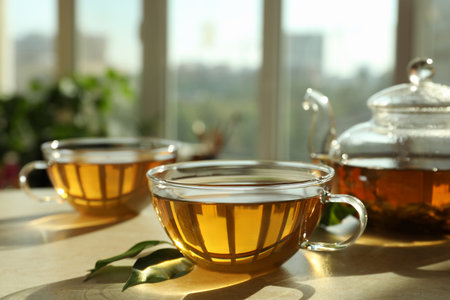 Fresh green tea in glass cups, leaves and teapot on table indoorsの写真素材