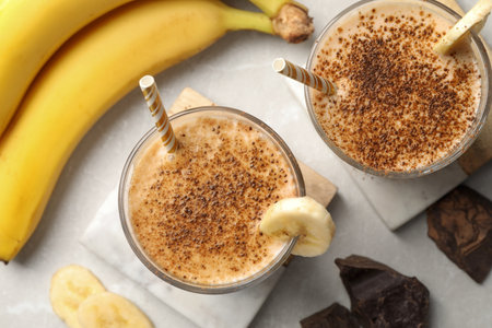 Tasty banana smoothie, fresh fruits and chocolate on white marble table, flat layの写真素材