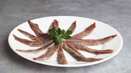 Plate with anchovy fillets and parsley on gray table, closeupの写真素材
