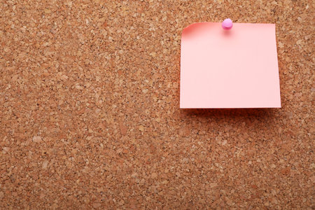 Blank paper note pinned to cork background. Space for textの写真素材