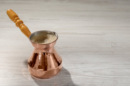 Cezve with hot aromatic Turkish coffee on white wooden table, space for textの写真素材