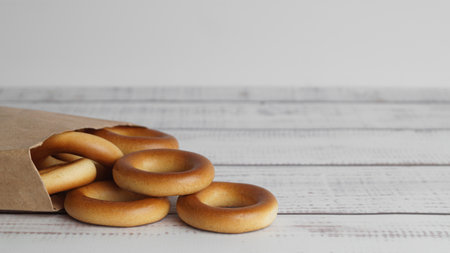 Bag with tasty dry bagels (sushki) on white wooden table, closeup. Space for textの写真素材