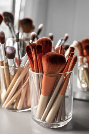 Set of professional makeup brushes near mirror on gray tableの写真素材
