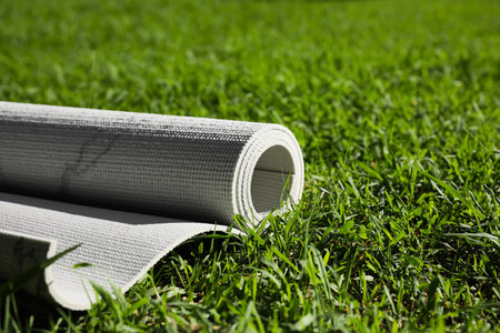 Karemat or fitness mat on green grass outdoors, closeup. Space for textの写真素材