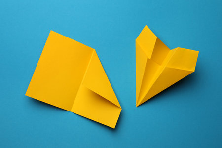 Handmade yellow plane and folded paper on light blue background, flat layの写真素材