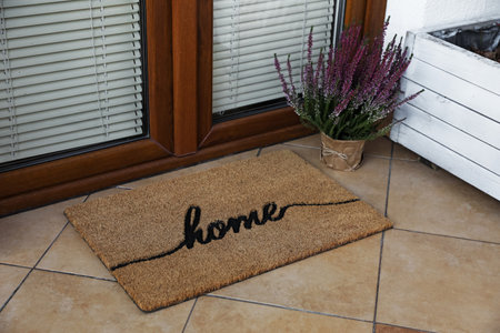 Doormat with word Home and flowers near entrance outdoorsの写真素材