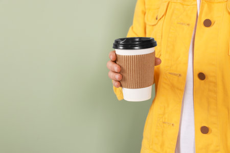 Woman holding takeaway cup with drink on pale green background, closeup view and space for text. Coffee to goの写真素材