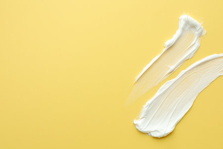 Samples of face cream on yellow background, top view. Space for textの写真素材