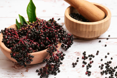 Tasty elderberries (Sambucus) on white wooden table