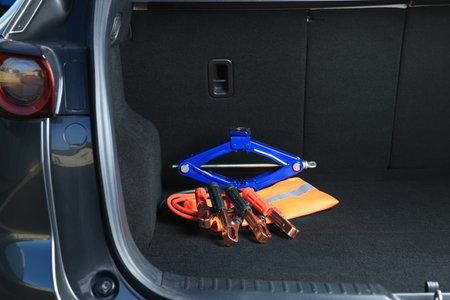 Scissor jack, life vest and battery jumper cables in trunk. car safety equipment