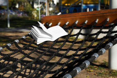 Comfortable net hammock with open book outdoors on sunny dayの写真素材