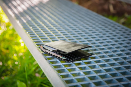 Black wallet on metal bench outdoors. lost and foundの写真素材