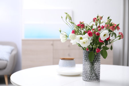 Vase with beautiful flowers on white table in room, space for textの写真素材