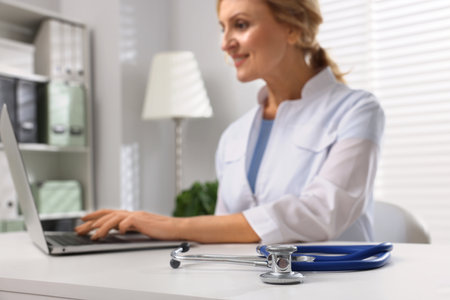 Doctor with laptop at white table, focus on stethoscope. Patient consultationの写真素材