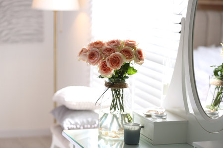 Glass vase with beautiful flowers on dressing table in modern room interiorの写真素材