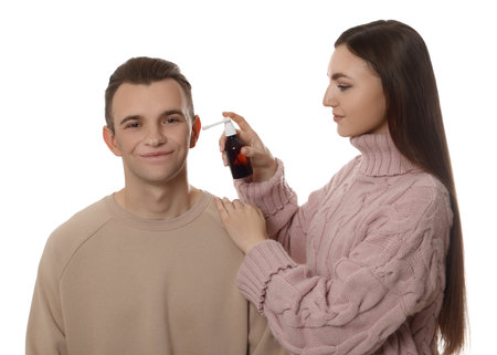 Woman spraying medication into man's ear on white backgroundの写真素材