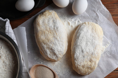 Raw dough, eggs and flour on wooden table, flat lay. Cooking ciabatta