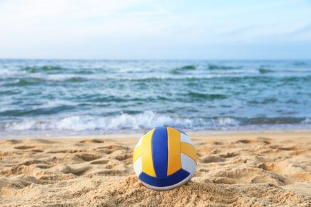 Colorful volleyball ball on sand near the seaの写真素材