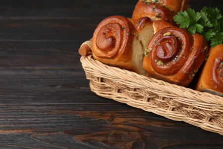 Delicious pampushky (buns with garlic) in wicker basket on wooden table, space for textの写真素材