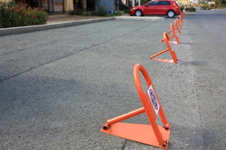 Many parking barriers with No Stopping signs on asphalt in city. Space for text