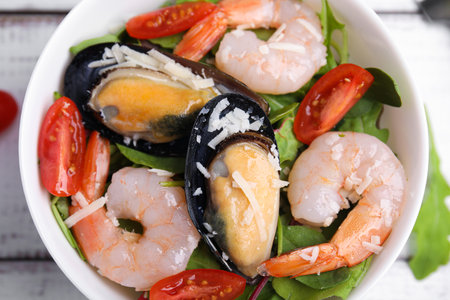 Bowl of delicious salad with seafood on white wooden table, top viewの写真素材
