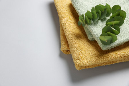 Soft folded towels with eucalyptus branches on light gray background. Space for textの写真素材