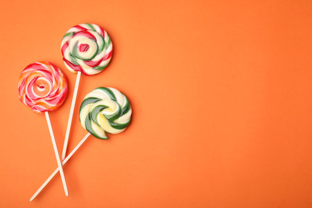 Colorful lollipops on orange background, flat lay. Space for textの写真素材