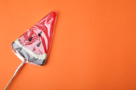 Watermelon shaped lollipop on orange background, top view. Space for textの写真素材