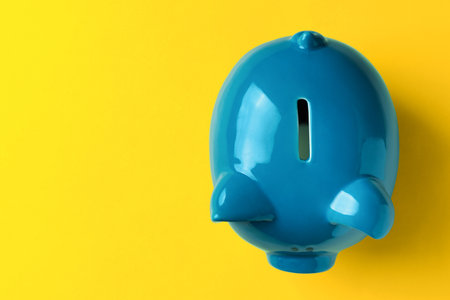 Ceramic piggy bank on yellow background, top view. Space for textの写真素材