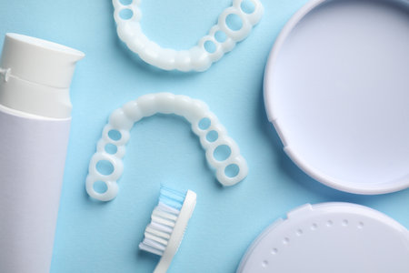 bit correction. Toothpaste, brush, container and dental mouth guards on light blue background, flat...