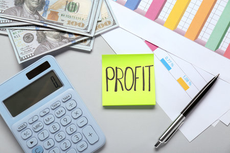 Sticky note with word Profit, calculator, banknotes and diagram on light gray background, flat lay