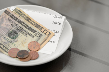 Tips and receipt on wooden table in outdoor cafeteria, closeupの素材 [FY310195876153]