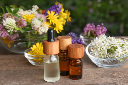 Bottles of essential oils and many beautiful flowers on wooden tableの写真素材