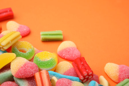 Many different jelly candies on orange background, closeup. Space for textの写真素材