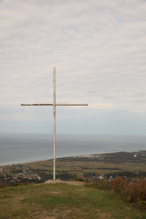 Picturesque view of beautiful sea and old cross under cloudy skyの写真素材