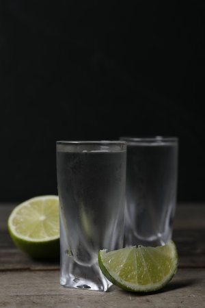 Shot glasses of vodka with lime on wooden table. Space for textの写真素材