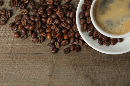 Cup of aromatic coffee and beans on wooden table, flat lay. Space for textの写真素材