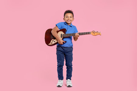 African-American boy with electric guitar on pink backgroundの写真素材