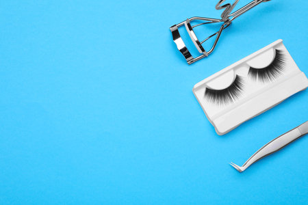 Flat lay composition with fake eyelashes and tools on light blue background. Space for textの写真素材